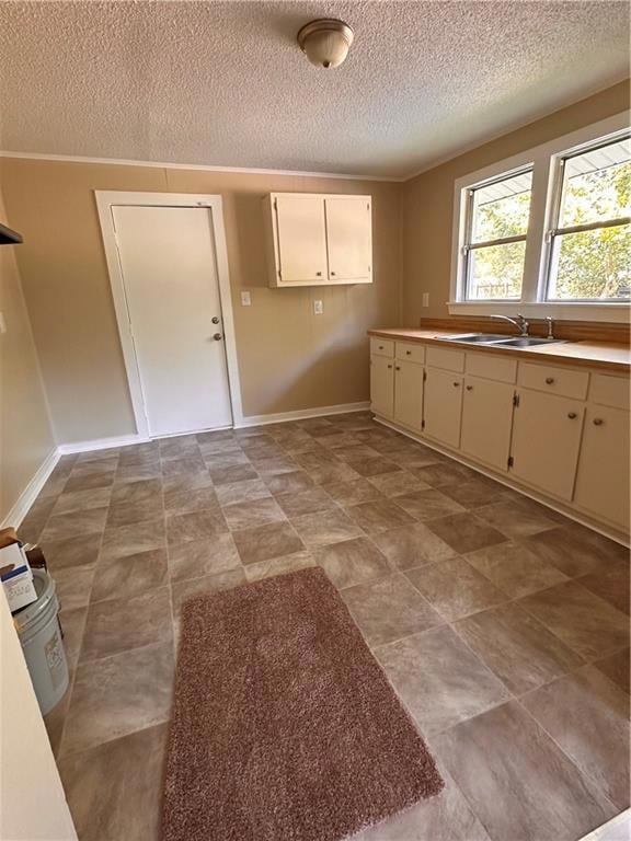 Kitchen featuring light countertops, ornamental molding, and a textured ceiling
