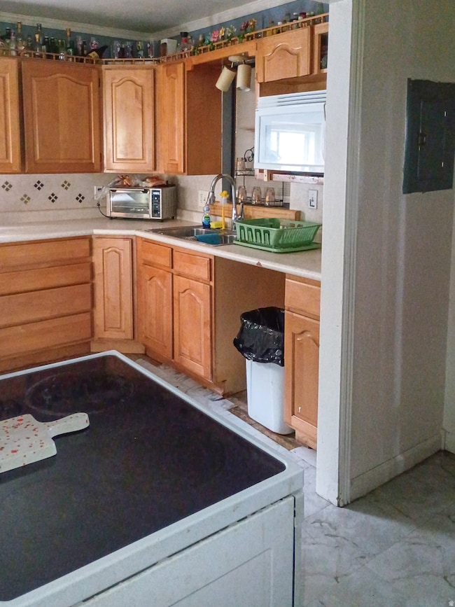 Kitchen featuring washer / clothes dryer, light countertops, white microwave, electric panel, and light marble finish floors