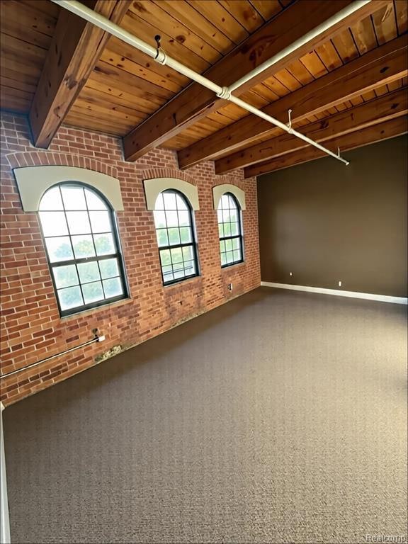 Unfurnished room with brick wall, a wooden ceiling with exposed beams, and carpet floors