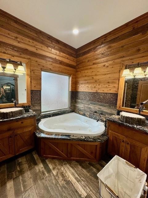 Bathroom with a bath, wood-type flooring, vanity, and wood walls