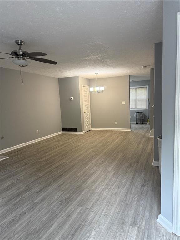 Spare room with wood finished floors, a ceiling fan, a textured ceiling, and a chandelier