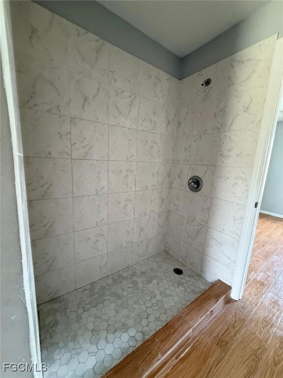 Bathroom featuring a tile shower and wood finished