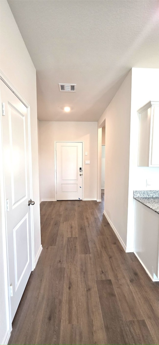 Hall featuring dark wood-style flooring and baseboards