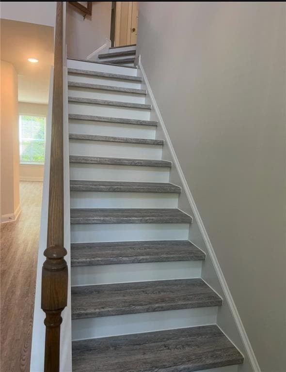 Stairs with baseboards, wood finished floors, and 