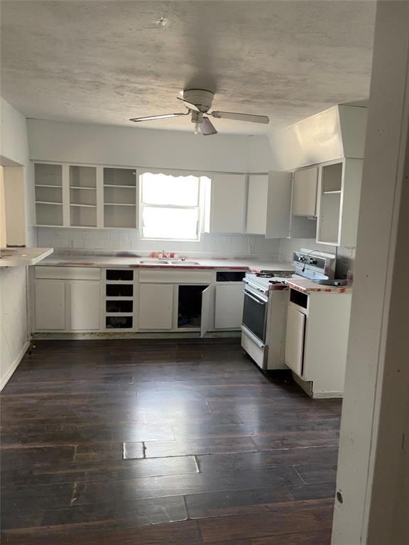 Kitchen with white stove, sink, white cabinetry, d