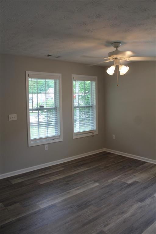 Empty room featuring dark wood-type flooring, baseboards, and a textured ceiling