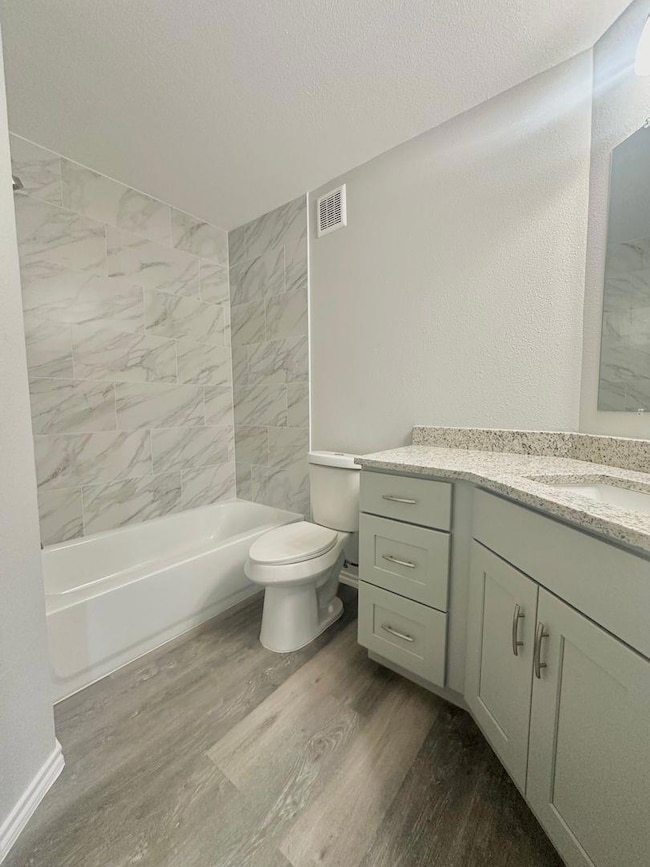 Bathroom with vanity, dark wood-style flooring, tub / shower combination, and a textured ceiling