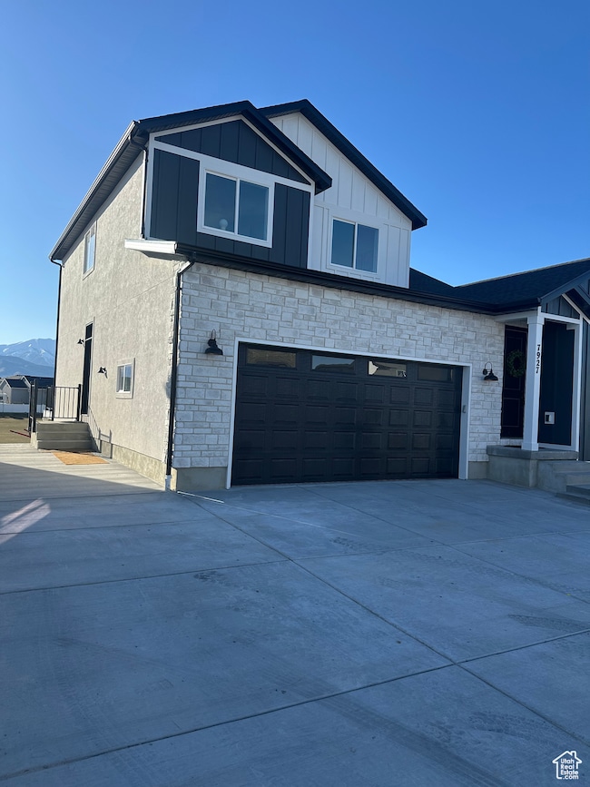 View of front of property featuring stone siding, board and batten siding, and concrete driveway