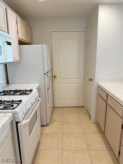 Kitchen featuring white appliances, tile counterto