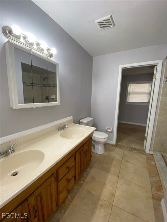 Bathroom with double vanity, light tile patterned floors, and tiled shower