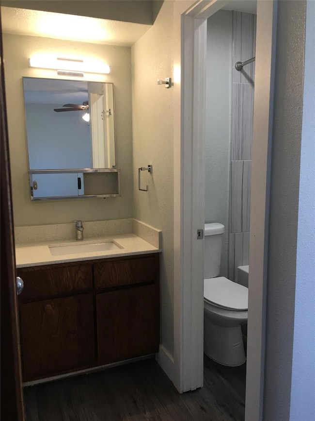 Bathroom with toilet, wood finished floors, a sho