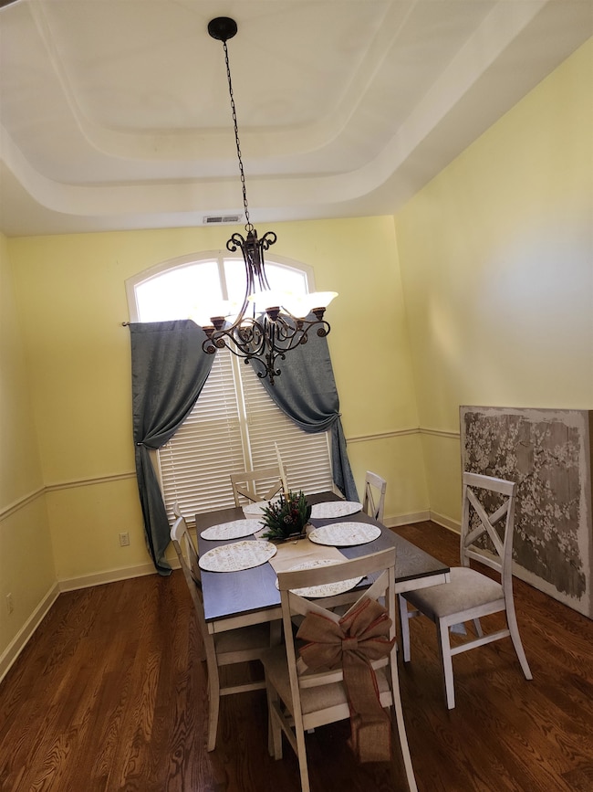Dining area with a tray ceiling, dark hardwood / w