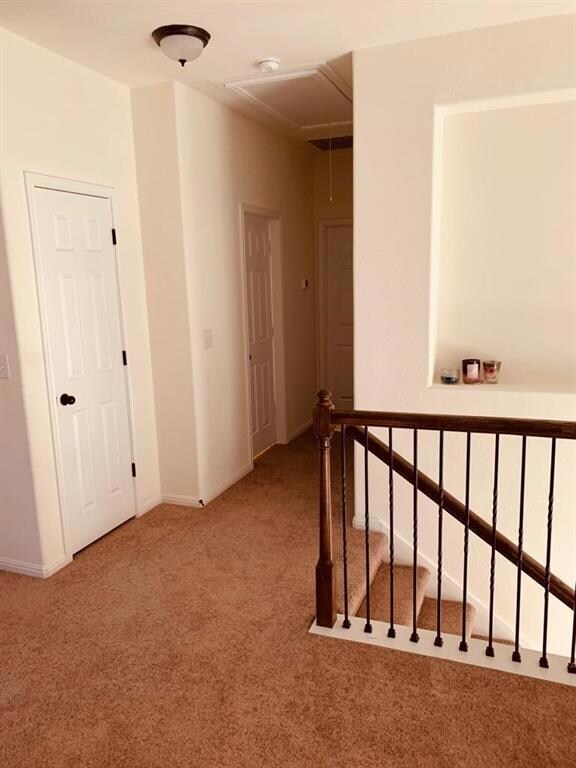 Corridor with attic access, carpet, and an upstai