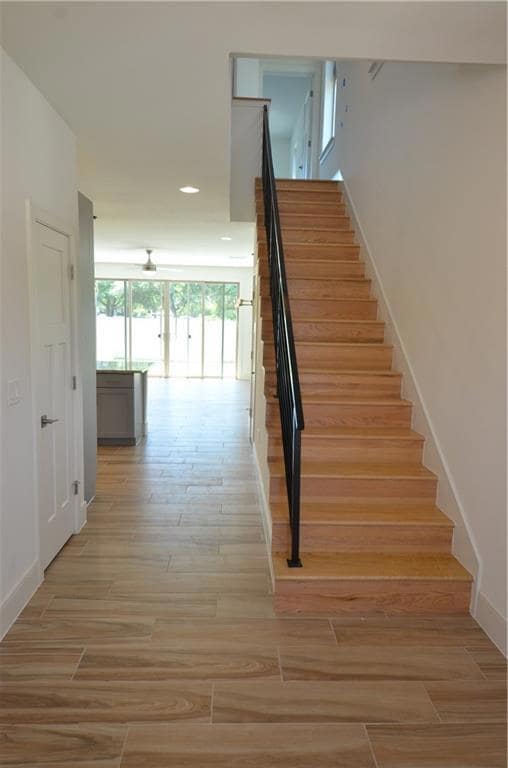 Stairway with wood finished floors, baseboards, a