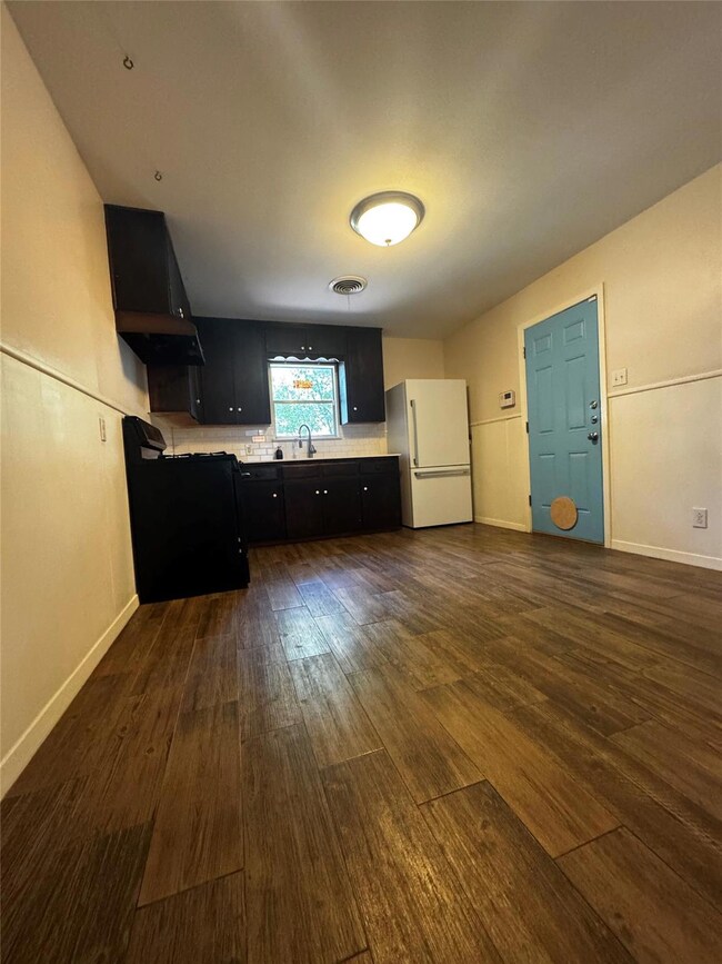 Unfurnished living room with dark wood-style floo