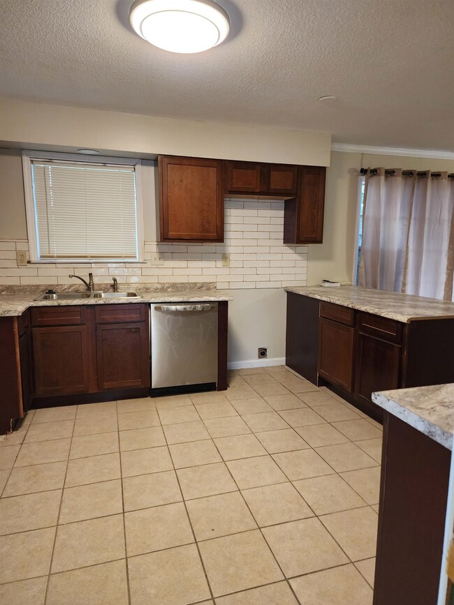 Kitchen with dishwasher, sink, light tile flooring