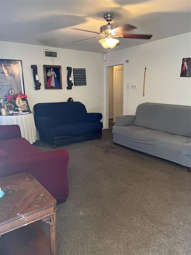 Carpeted living room featuring ceiling fan