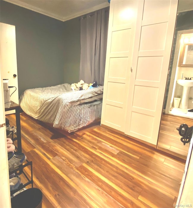 Bedroom with dark wood-type flooring and crown molding