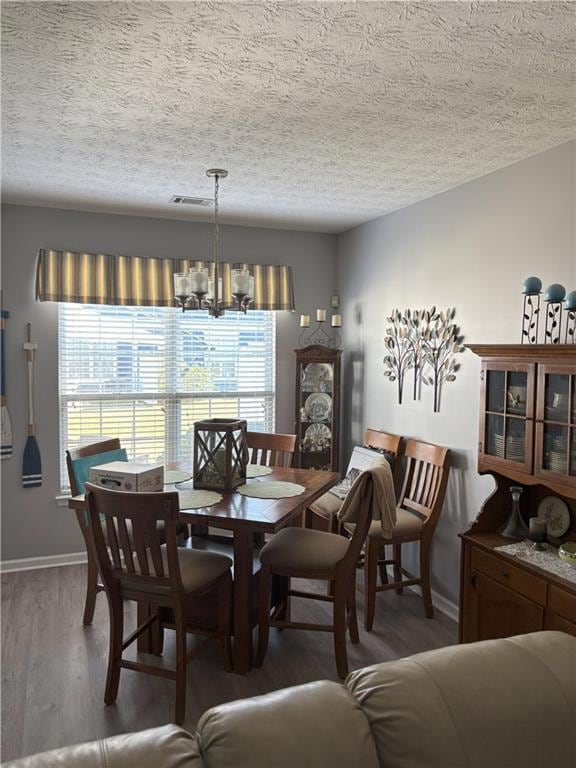 Dining area with wood finished floors, a textured ceiling, and a chandelier