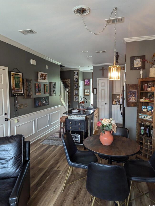 Dining area featuring crown molding, stairs, a chandelier, and dark wood-style flooring