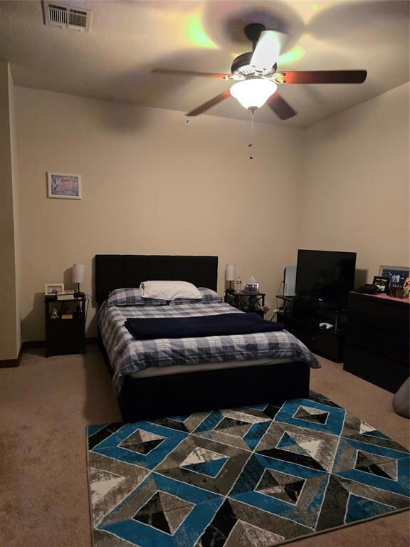 Carpeted bedroom featuring ceiling fan