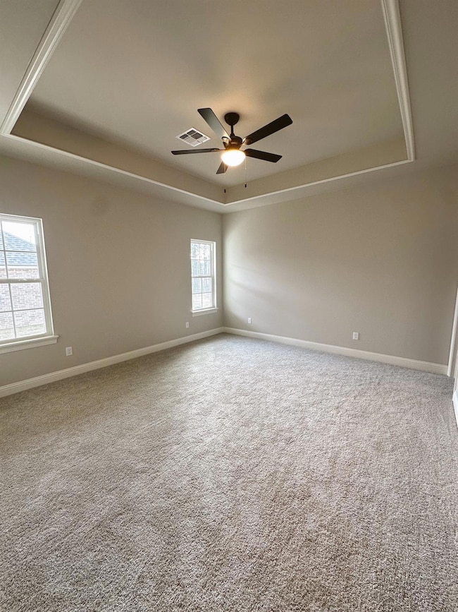Carpeted spare room featuring ceiling fan and a ra