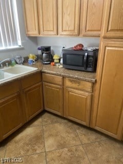 Kitchen featuring black microwave, a sink, and lig