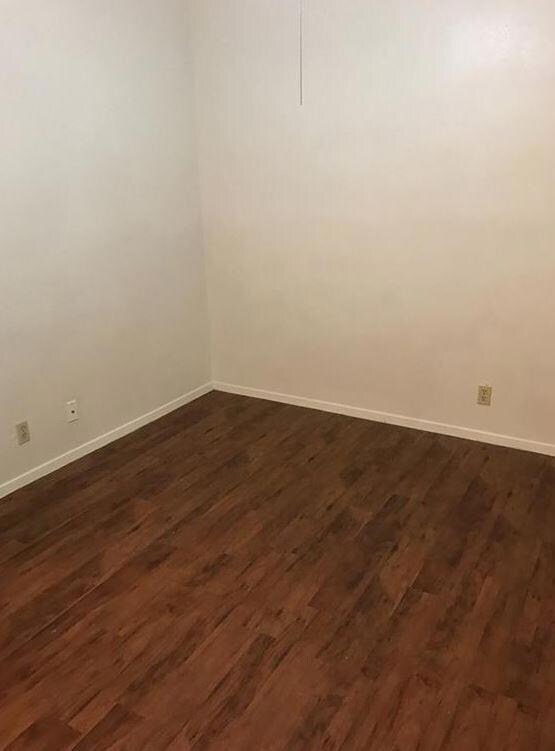 Spare room featuring dark wood-type flooring and 