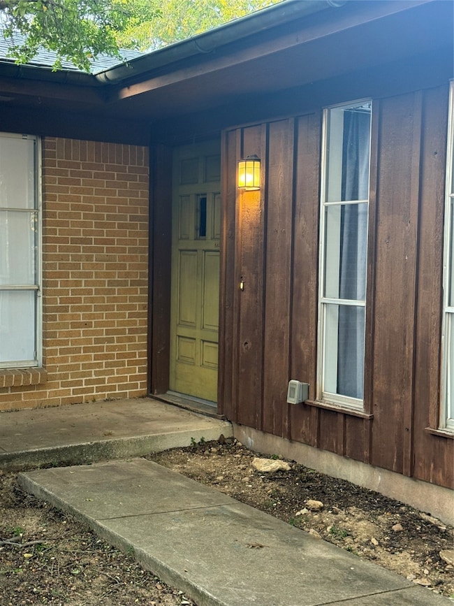 Property entrance featuring board and batten siding and brick siding