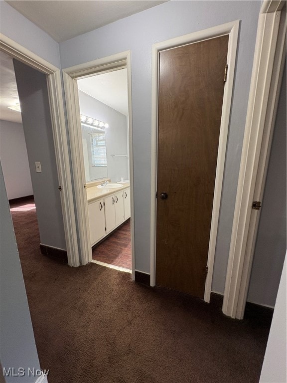 Hall featuring dark colored carpet