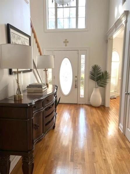 Entrance foyer with a high ceiling, light wood-type flooring, and stairs