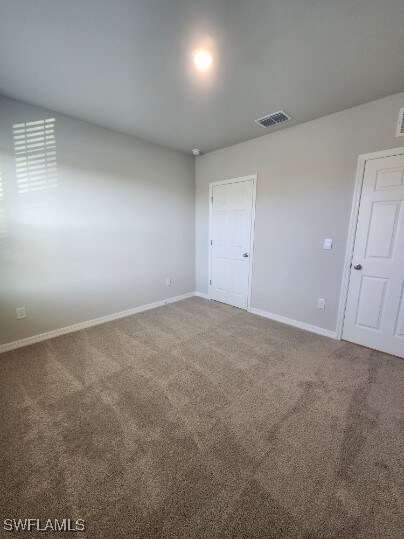 Carpeted spare room with baseboards and visible ve