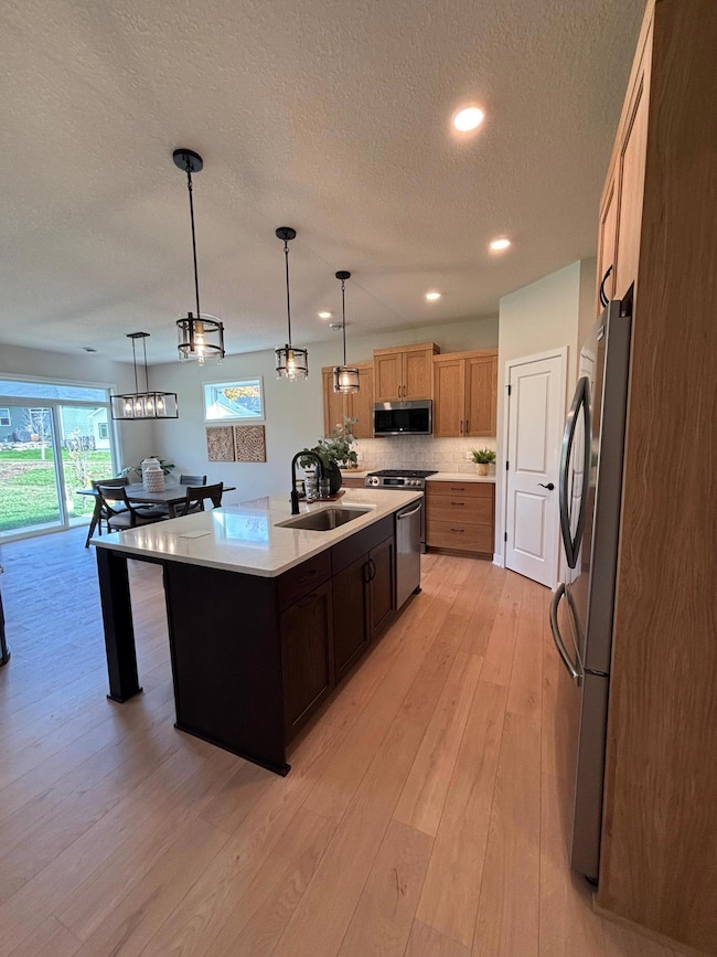 The white oak kitchen features an extended island with a large center sink, ideal for cooking and gathering. A corner pantry offers abundant storage, while the warm cabinetry blends style and function for a space that’s both inviting and practical.