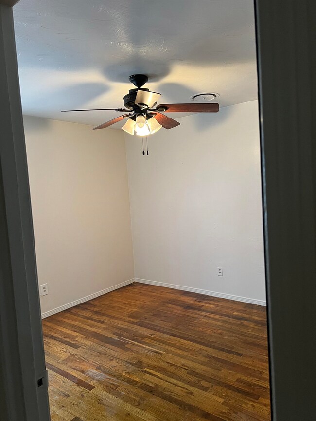 Unfurnished room featuring ceiling fan and dark wo