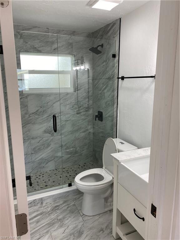 Bathroom featuring vanity, toilet, and a shower wi