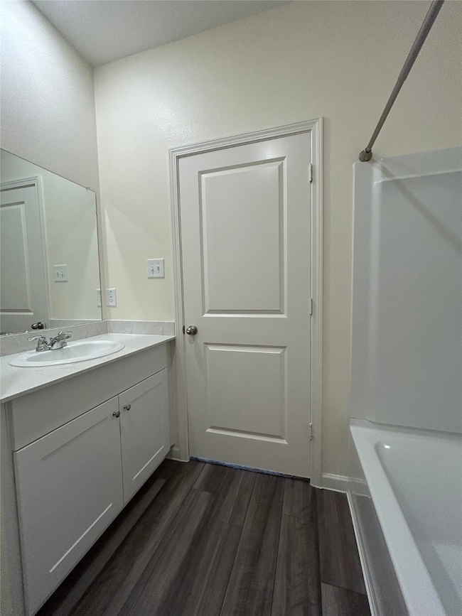 Full bathroom featuring dark wood-style floors, vanity, and tub / shower combination