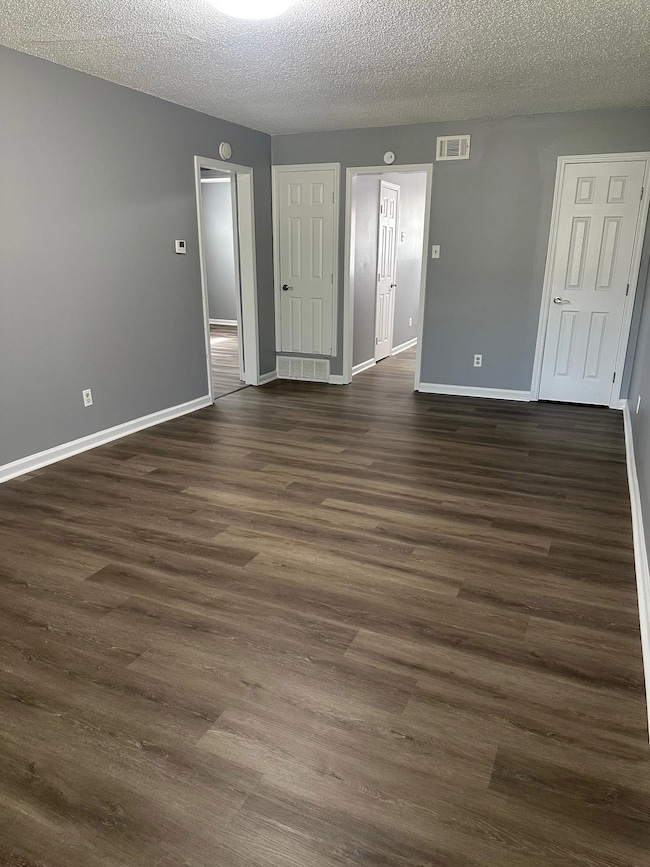 Unfurnished room with dark wood finished floors, baseboards, and a textured ceiling