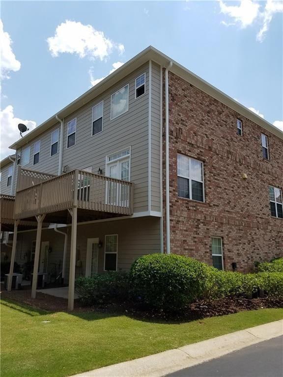 Rear view of property with brick siding, a patio area, and a yard