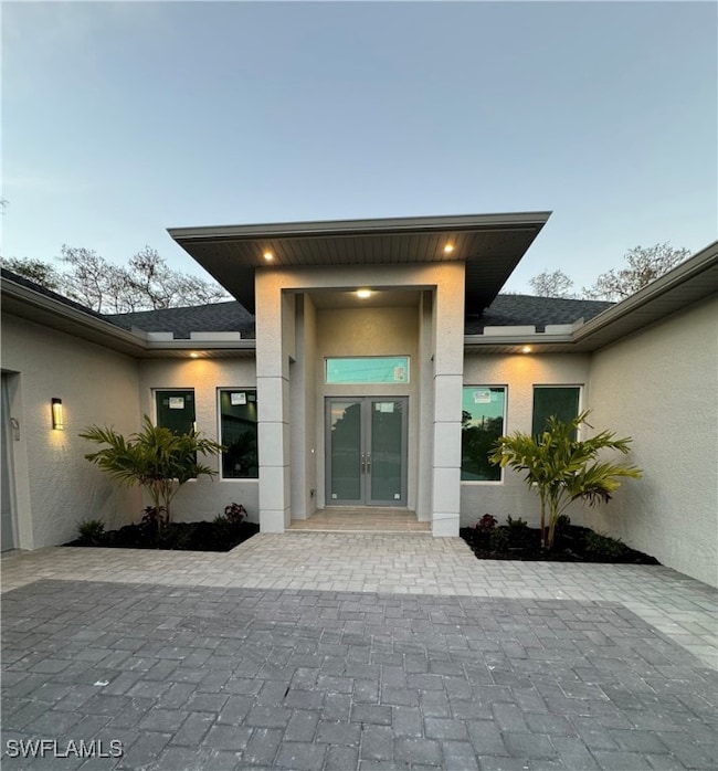 Doorway to property featuring a shingled roof, fre
