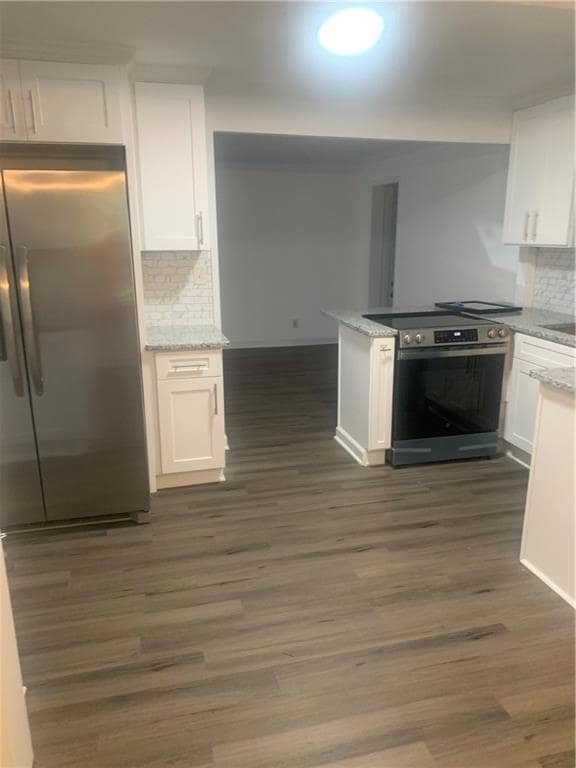 Kitchen featuring white cabinetry, fridge, stove, and dark hardwood / wood-style floors