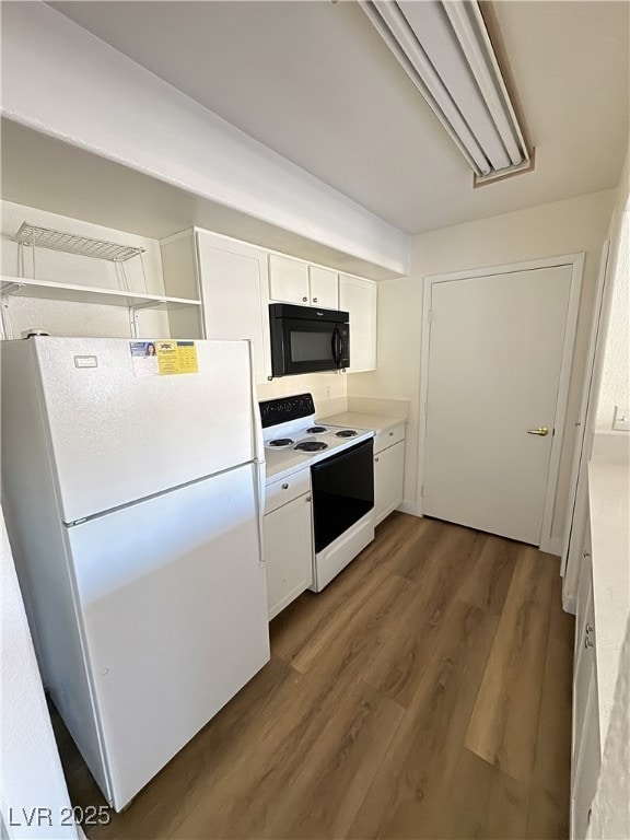 Kitchen featuring white cabinets, white appliances, light countertops, and dark wood finished floors