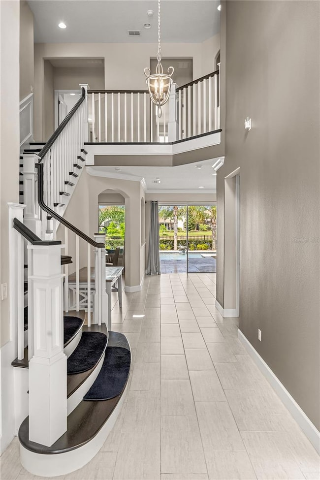 This soaring two-story foyer makes an unforgettable first impression, centered by a sculptural designer staircase that defines the home's elevated aesthetic. Just beyond, a custom pool spans the full length of the residence, merging interior elegance with resort-level outdoor living.