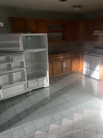 Kitchen with tile countertops, light tile flooring, white fridge, wall chimney exhaust hood, and range