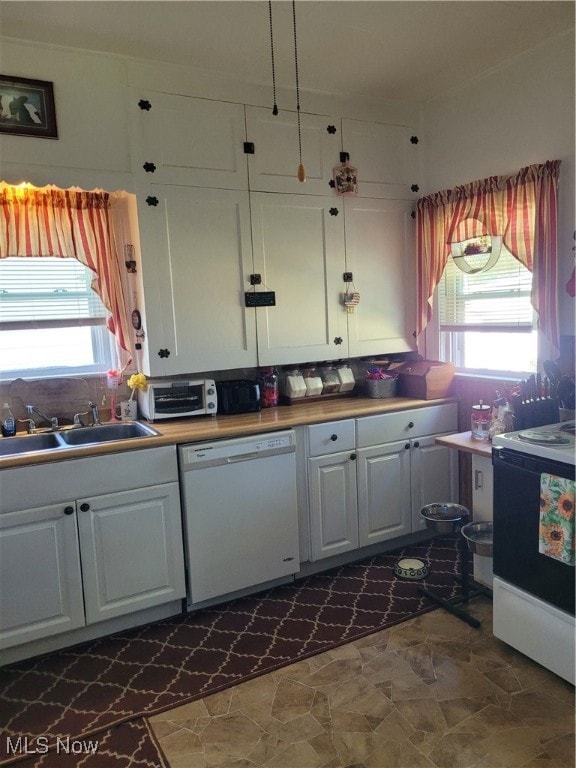 Kitchen featuring stove, dishwasher, white cabinetry, and dark stone finish flooring