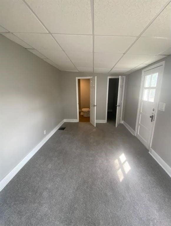 Unfurnished bedroom with a drop ceiling, carpet floors, and ensuite bath