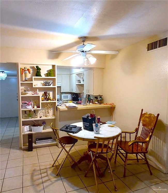Dining room with light tile patterned floors, a ceiling fan, and a textured ceiling