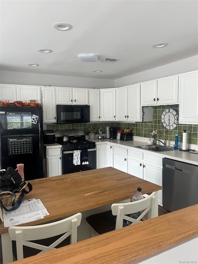 Kitchen with white cabinets, black appliances, backsplash, wood counters, and recessed lighting