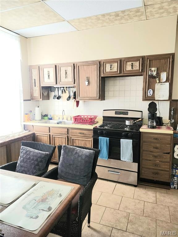 Kitchen featuring tasteful backsplash, stainless steel range with gas stovetop, light countertops, and light tile patterned flooring