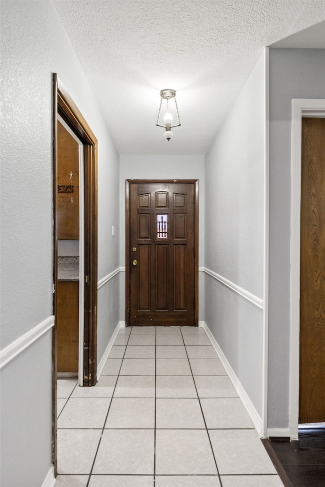 Doorway featuring tile patterned flooring and a textured ceiling