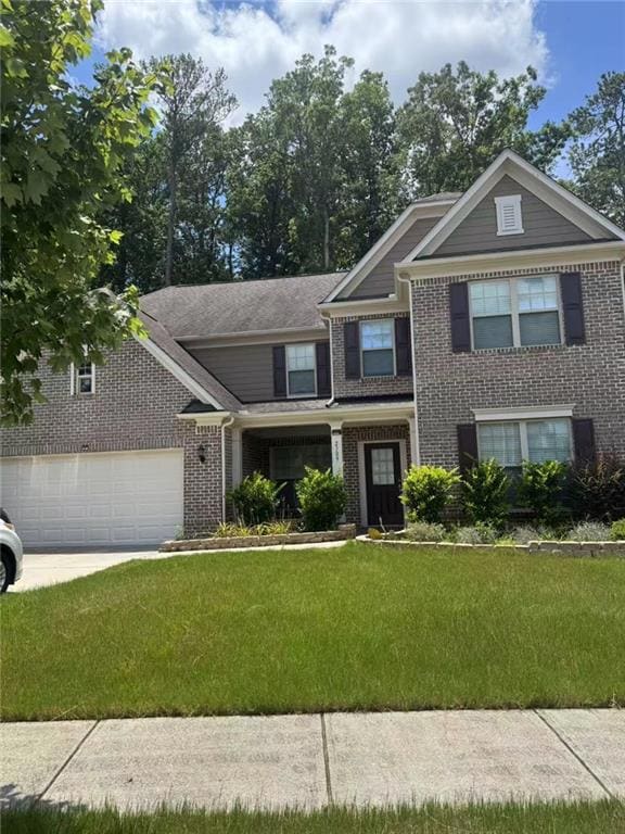 View of front of home with brick siding, a front lawn, driveway, and a garage